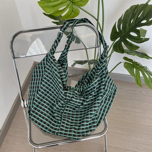 Detailed shot of a green and black checkered fabric tote bag on a modern chrome chair