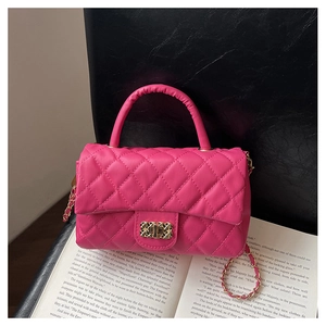 Close-up of pink quilted crossbody bag with gold buckle on an open book background