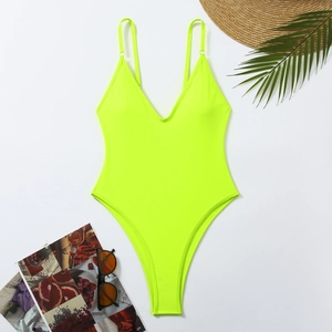 Flat lay of neon green one-piece swimsuit with deep V-neck, high-cut leg and summer accessories