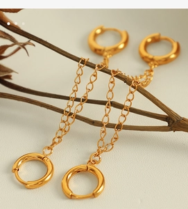 Close-up of elegant gold long chain drop earrings with dual hoops hanging on a branch
