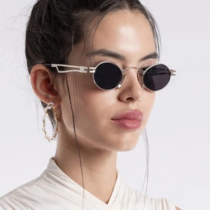 Close-up of vintage small oval silver metal sunglasses with black lenses on model