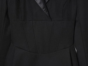 Détail du col en V et taille ajustée sur une robe blazer noire à manches longues et satin