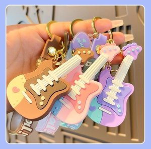 Close-up of colorful soft silicone guitar keychains held in hand with guitar text
