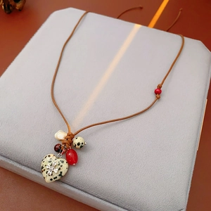 Close-up of heart-shaped stone pendant with dragonfly detail and colorful beads necklace