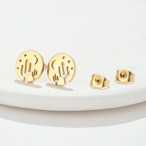 Golden openwork stud earrings with cactus, crescent moon and star patterns on white background