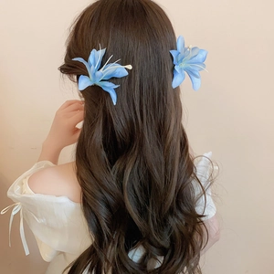 Detailed close-up of gradient blue fabric hibiscus hair clips on long wavy hair