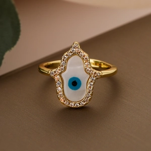 Golden Hamsa hand ring with evil eye center and zircon pavé setting on textured surface