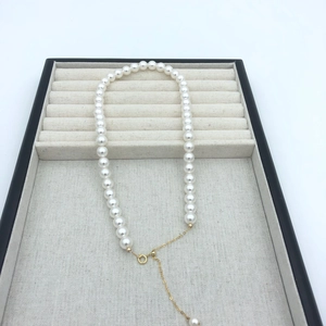 Detail of round white pearl necklace with 14k gold adjustable clasp on jewelry tray