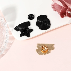 Three alloy pins with butterfly clasps on a stylish pink background with floral accents