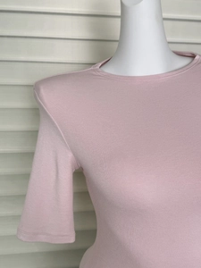 Detail of pink knitted top showing fine ribbed texture and padded shoulder construction