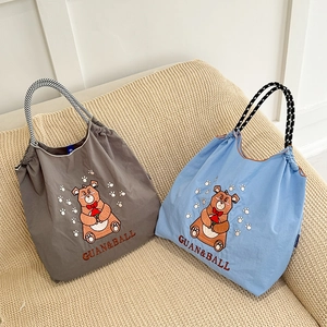 Close-up of gray and blue nylon tote bags with bear embroidery and checkered handles