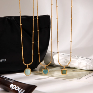 Detail view of blue cat eye stone pendants in heart, oval, and square shapes on gold chains