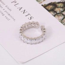Close-up of minimalist silver open ring with paved cubic zirconia on white background