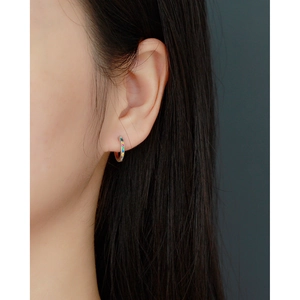 Close-up of small silver S925 huggie hoop earring featuring a rainbow of inset gemstones