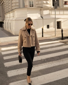 Street style shot of a khaki double-breasted short trench coat with black slim-fit pants