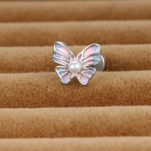 Vue macro d'une boucle d'oreille papillon avec émail rose-bleu et incrustation de perle