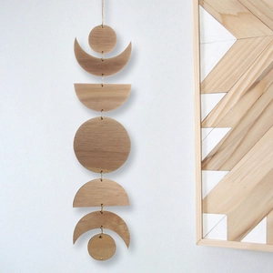 Detail view of natural wood moon phase wall hanging decoration on a white wall