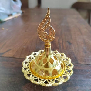 Close-up of golden hollow metal incense burner with elegant flame-shaped carvings