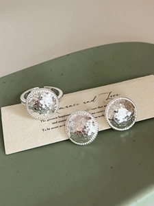 Detailed view of silver hammered round earrings and open ring on a ceramic tray