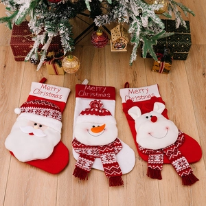 Three knitted Christmas stockings with 3D Santa, Snowman and Reindeer dolls by a tree