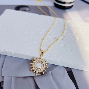 Close-up of gold plated sunburst pendant with zircon and pearl details on chain