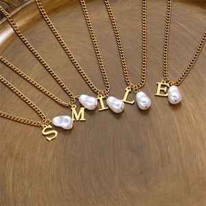 Gold plated letter necklace with baroque pearls spelling SMILE on a vintage tray