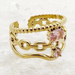 Macro detail of a gold-plated multi-layer chain ring featuring two pink gemstones