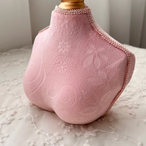 Detail of pink velvet jewelry bust stand with embossed floral patterns and lace trim
