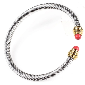 Detail of twisted cable cuff with golden sphere ends and inlaid red round gemstones