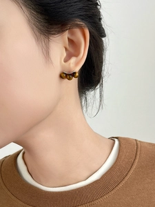 Macro detail of tiger eye stone earrings with silver posts in a minimalist three-bead design