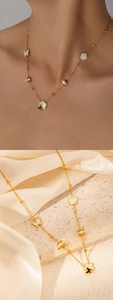Détail d'un collier en titane doré avec pendentifs papillon et fleur ornés de cristaux