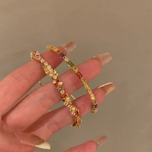 Dettaglio macro di braccialetti placcati oro con cristalli colorati e pietre preziose
