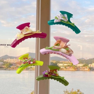 Detail of vibrant acetate tulip hair claws in multiple colors against a scenic lake
