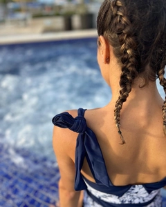 Detail of navy blue swimwear with bow tie straps and floral pattern against a pool