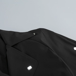 Détail d'une robe blazer noire élégante avec boutons carrés en strass sur l'épaule
