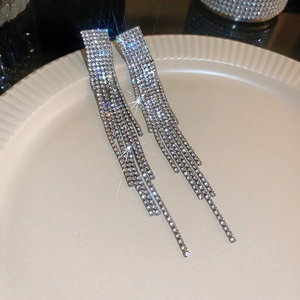 Gros plan de boucles d'oreilles pampilles argentées avec strass sur plateau céramique
