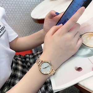 Elegant rose gold watch with crystal-encrusted dial shown in a cozy cafe setting