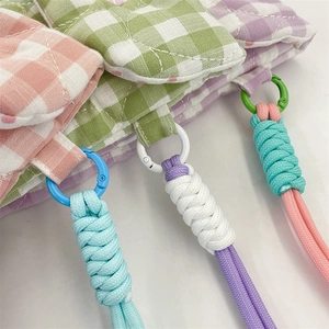 Detail of colorful braided lanyards on pastel checkered padded camera storage bags