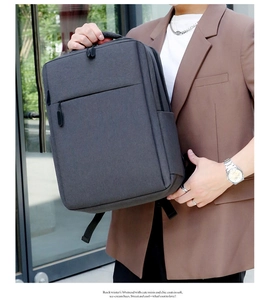 Close-up of a grey fabric business backpack held by a model in a professional suit