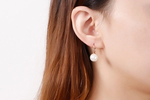 Gros plan de boucles d'oreilles perles blanches avec crochets or rose sur le modèle