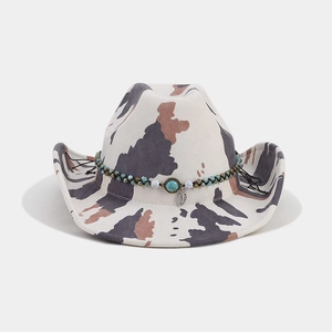 Detail of white cow print western cowboy hat with turquoise beads and silver leaf pendant
