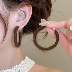 Brown flocking round hoop earrings in retro minimalist style for women on ear