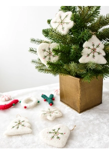 Detailed view of handmade white wool felt Christmas ornaments with green snowflake embroidery