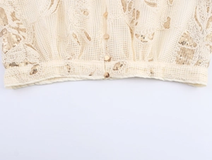 Detail of beige lace cardigan featuring golden sequins and metallic round buttons