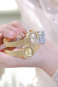 Close-up of golden and silver vintage square watches with crystal bezel and woven band