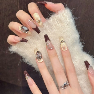 Detailed macro of coffee cat-eye press-on nails with luxury rhinestones and gold accents