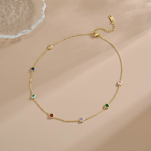 Elegant 18K gold chain bracelet with colorful gemstones on a soft beige background