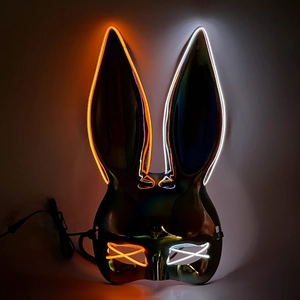 Macro detail of LED bunny mask with glowing orange and white EL wire on iridescent surface