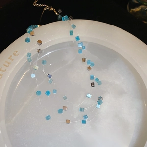 Detailed macro of layered necklace with blue opal beads and silver cubes on stone tray