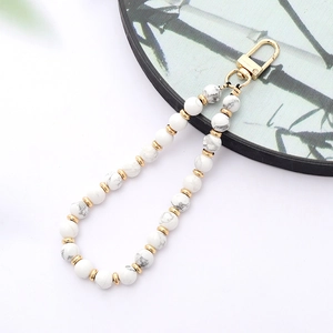 Detail of white turquoise beaded phone strap with gold lobster clasp and spacers